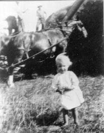 Mary Jane Deck as a little girl with a threshing crew in the background